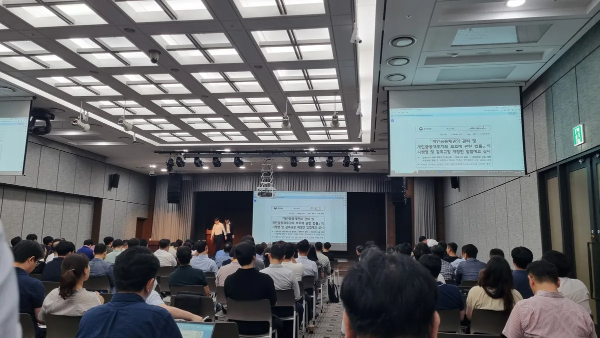 은행회관 국제회의실에서 열린 개인채무자보호법 시행령 및 감독규정 제정안 입법예고 설명회 현장. 대형 스크린에 금융위원회 보도자료가 띄워져 있고 참석자들이 자리를 가득 메우고 있다.
